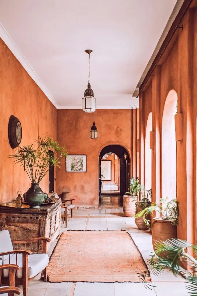 Rustic terracotta corridor with arched windows, potted plants, and Moroccan-style decor